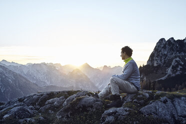 Austria, Tyrol, Rofan Mountains, hiker sitting on rocks at sunset - RBF06226