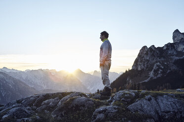 Austria, Tyrol, Rofan Mountains, hiker standing on rocks at sunset - RBF06227