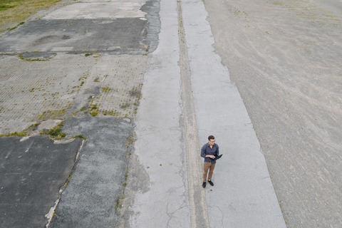 Young businessman using laptop in solitude, quadcopter view stock photo