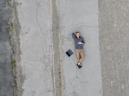 Junger Geschäftsmann mit Laptop entspannt in der Einsamkeit, Quadcopter-Ansicht - KNSF03240