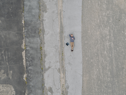 Young businessman with laptop relaxing in solitude, quadcopter view stock photo