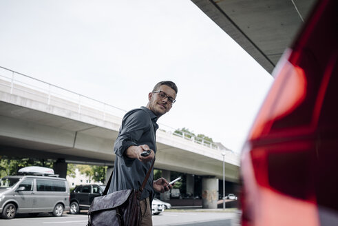 Young businessman using remote control key of car - KNSF03254