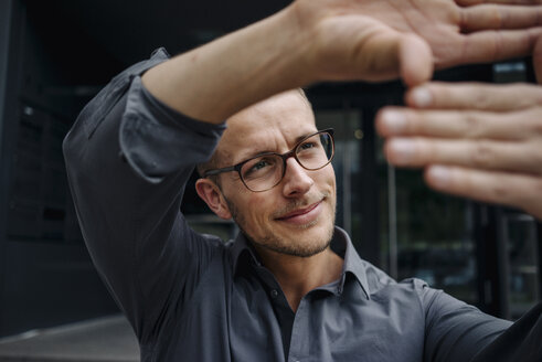 Portrait of smiling businessman making finger frame - KNSF03256