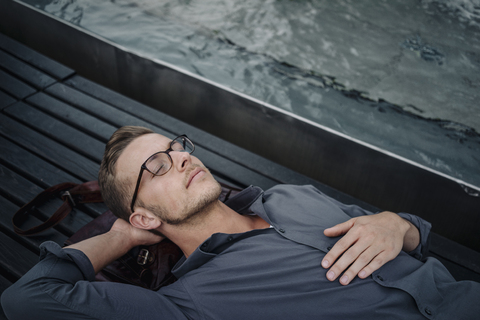 Porträt eines jungen Geschäftsmannes, der sich auf einer Bank ausruht, lizenzfreies Stockfoto