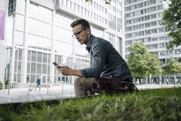 Young businessman using smartphone outdoors - KNSF03261