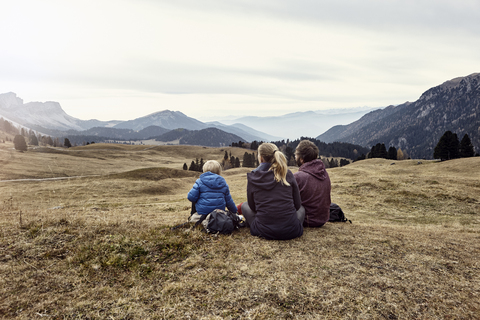 Italy, South Tyrol, Geissler group, family hiking, sitting on meadow stock photo