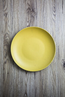 Leerer gelber Teller auf Holz - GIOF03709