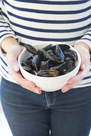 Woman holding bowl with fresh blue mussels stock photo