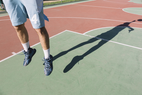 Man playing basketball, jumping, shadow stock photo