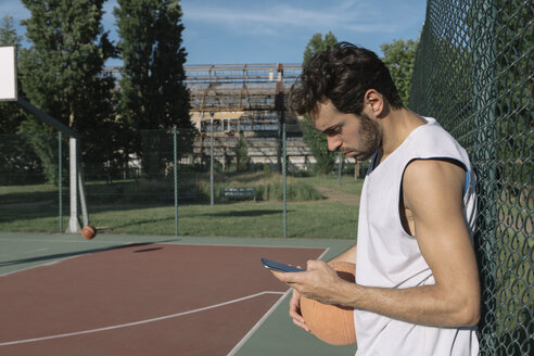 Basketballspieler schaut auf sein Smartphone - ALBF00334