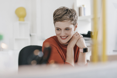 Porträt einer lächelnden Frau am Schreibtisch im Büro, lizenzfreies Stockfoto