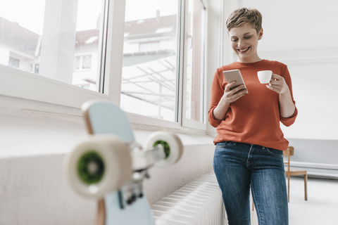 Lächelnde Frau mit Mobiltelefon und Espressotasse, lizenzfreies Stockfoto