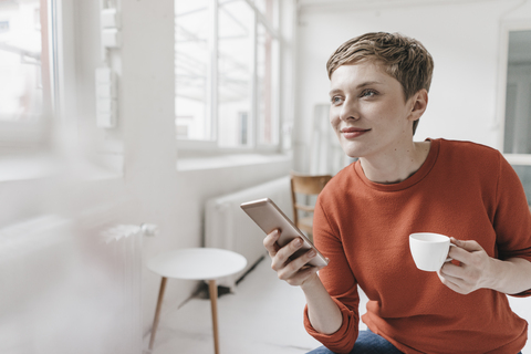 Smiling woman with cell phone and espresso cup stock photo