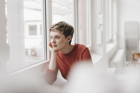 Pensive woman looking out of window stock photo