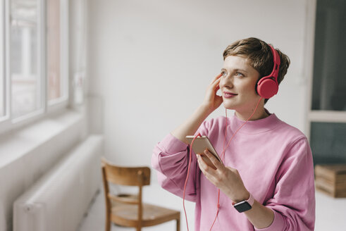 Lächelnde Frau mit Handy und Kopfhörern beim Musikhören - KNSF03282