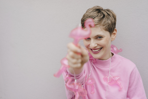 Porträt einer glücklichen Frau mit rosa Flamingo-Lichterkette, lizenzfreies Stockfoto