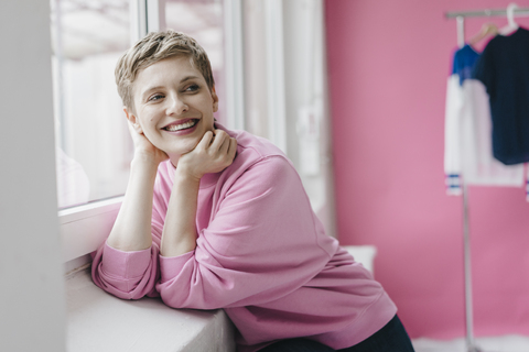 Happy woman wearing pink sweatshirt at the window stock photo