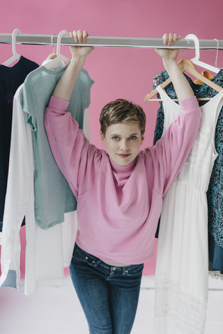 Portrait of smiling woman at clothes rail stock photo