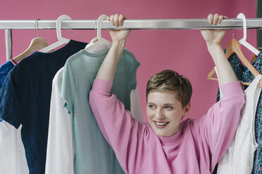 Portrait of smiling woman at clothes rail - KNSF03289