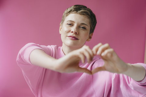 Portrait of woman in pink shaping heart with her hands stock photo