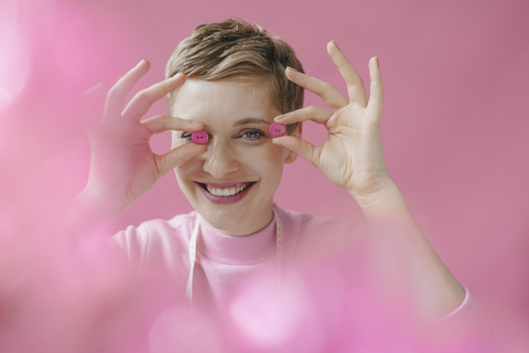 Portrait of happy tailoress holding pink buttons stock photo