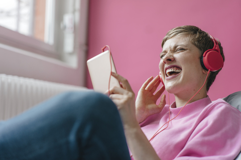 Screaming woman with cell phone and headphones listening to music stock photo