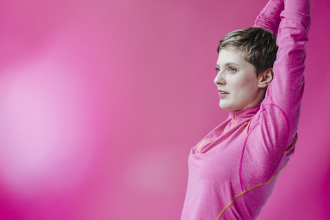 Woman in pink sportswear stretching her arms stock photo