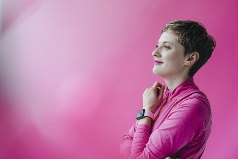 Frau in rosa Sportkleidung trägt Smartwatch, lizenzfreies Stockfoto