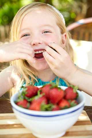 Portrait of happy girl eating stawberries stock photo