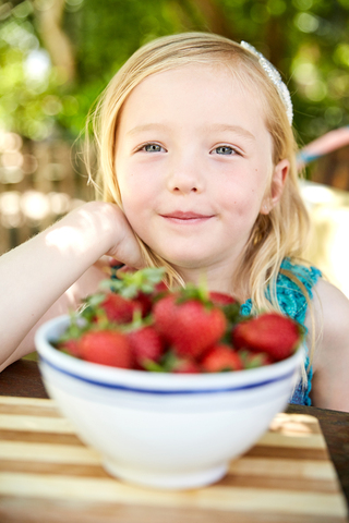 Porträt eines lächelnden Mädchens mit einer Schale Stawberries, lizenzfreies Stockfoto