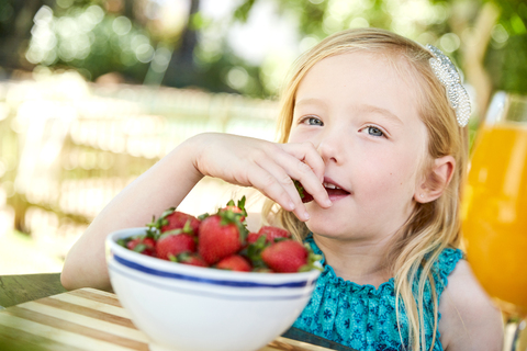 Porträt eines Mädchens, das Stawberries isst, lizenzfreies Stockfoto