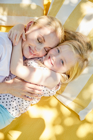 Happy girl hugging mother on a blanket stock photo
