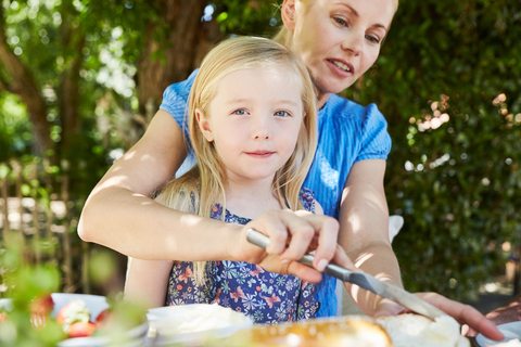 Girl with mother having breakfast at garden table stock photo