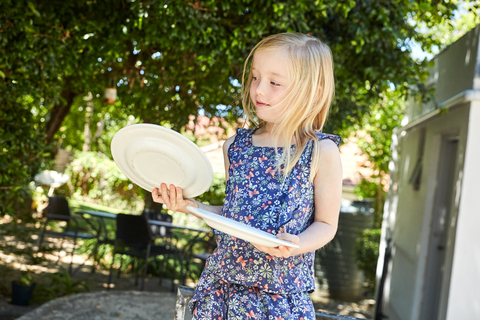 Blondes Mädchen hält Teller im Garten, lizenzfreies Stockfoto