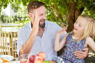 Glückliches Mädchen mit Vater am Gartentisch sitzend, High Fiving - SRYF00626