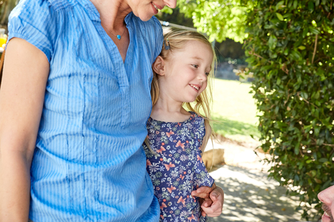 Mother embracing smiling girl outdoors stock photo