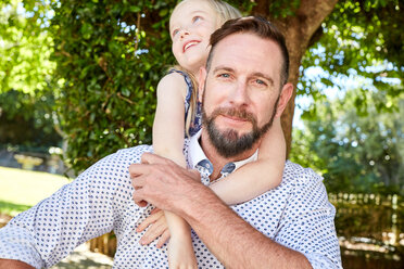 Portrait of smiling father carrying daughter piggyback - SRYF00640