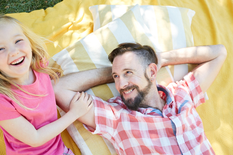 Glückliches Mädchen mit Vater auf einer Decke liegend, lizenzfreies Stockfoto