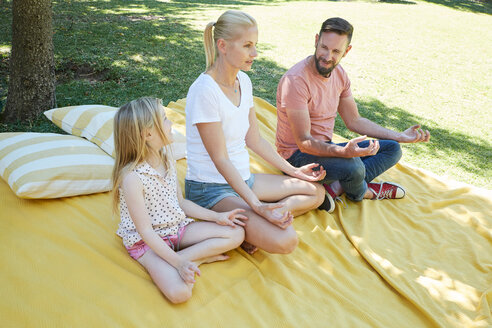 Familie mit Mädchen übt Yoga auf einer Decke - SRYF00658