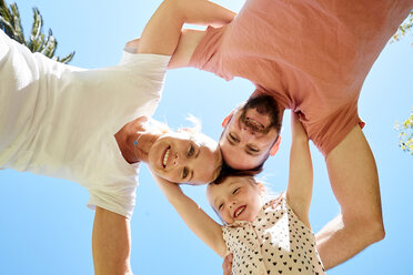 Porträt einer glücklichen Familie, die unter blauem Himmel kauert - SRYF00672