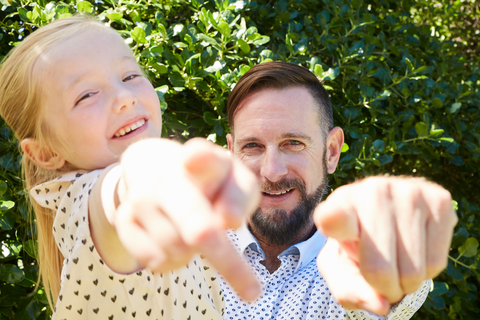 Portrait of happy father and daughter pointing their fingers stock photo