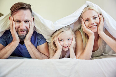 Portrait of happy family under blanket in bed - SRYF00689