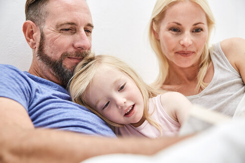 Glückliche Familie im Bett beim gemeinsamen Lesen eines Buches - SRYF00693