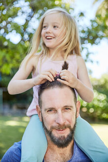 Glückliches Mädchen sitzt auf den Schultern des Vaters und frisiert ihn - SRYF00696
