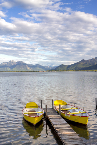 Germany, Bavaria, Chiemsee, Prien am Chiemsee, yellow rowing boats at boardwalk stock photo