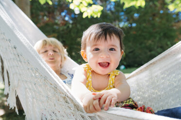 Spain, Grandma and baby relaxing in a hammock in the garden in the summer - GEMF01828