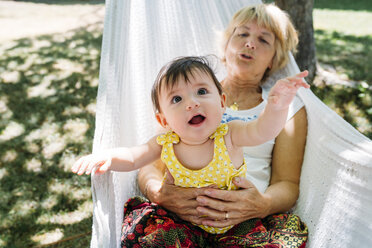 Spain, Grandma and baby relaxing in a hammock in the garden in the summer - GEMF01829
