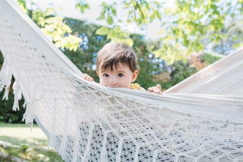 Spanien, Baby-Mädchen entspannt sich in einer Hängematte im Garten im Sommer, lizenzfreies Stockfoto