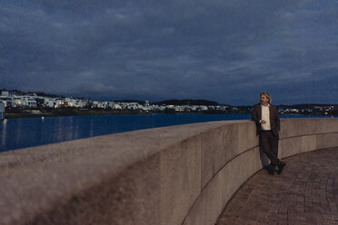 Älterer Mann steht abends am Seeufer - KNSF03340