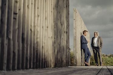 Two businessmen standing on boardwalk talking - KNSF03355